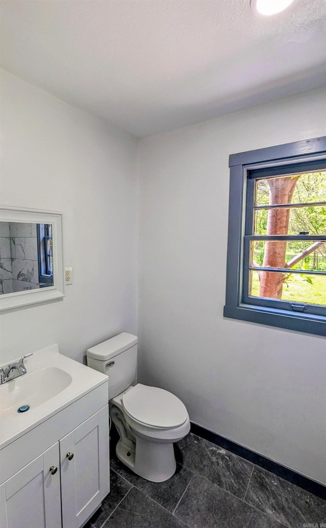 bathroom featuring baseboards, vanity, and toilet
