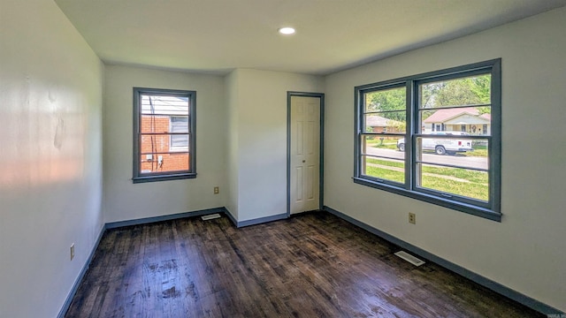 unfurnished room with recessed lighting, baseboards, visible vents, and dark wood-style floors