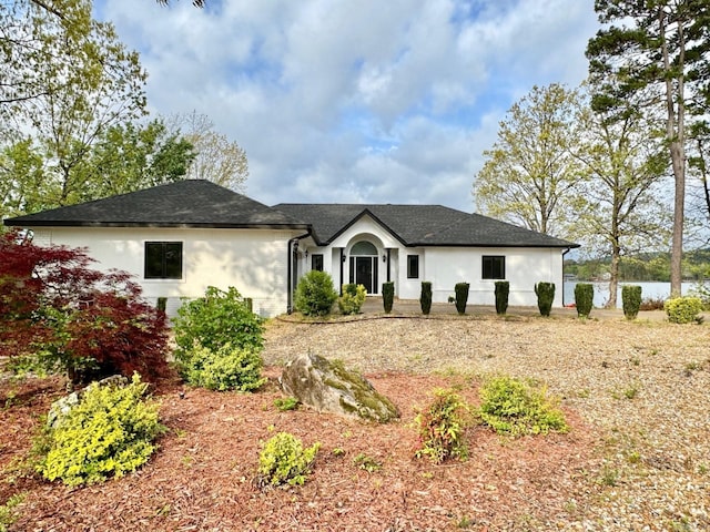 view of front facade featuring roof with shingles and stucco siding