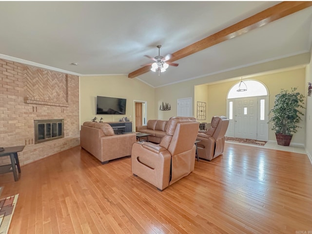 living area featuring a fireplace, light wood-style floors, vaulted ceiling with beams, and a ceiling fan