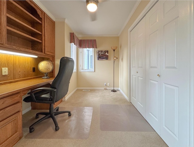 office featuring built in desk, ornamental molding, baseboards, light colored carpet, and ceiling fan