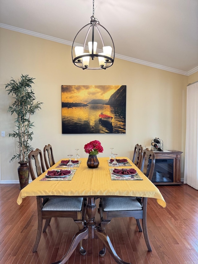 dining area with baseboards, ornamental molding, wood finished floors, and a chandelier
