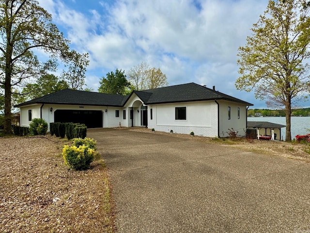 ranch-style home with an attached garage, aphalt driveway, brick siding, and a water view