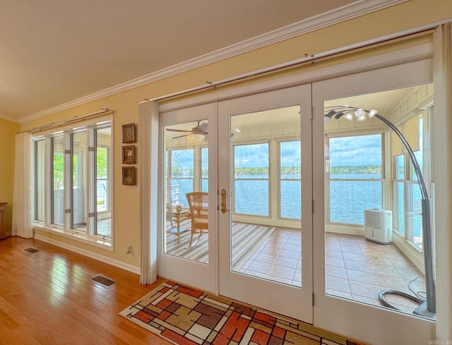 entryway with crown molding, wood finished floors, visible vents, and a water view
