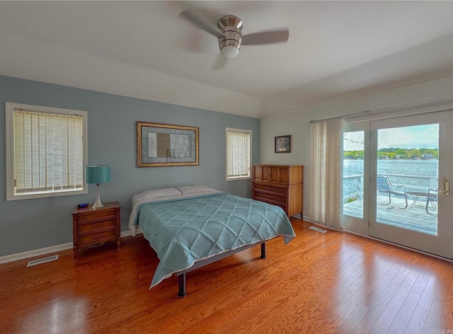 bedroom featuring multiple windows, wood finished floors, visible vents, and access to exterior