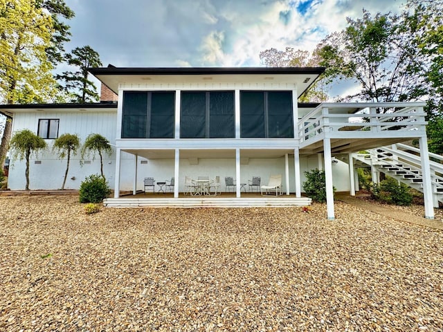rear view of property featuring a wooden deck, a sunroom, a patio area, and stairway