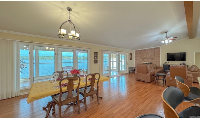 dining space featuring vaulted ceiling with beams, a fireplace, light wood-style floors, and ornamental molding