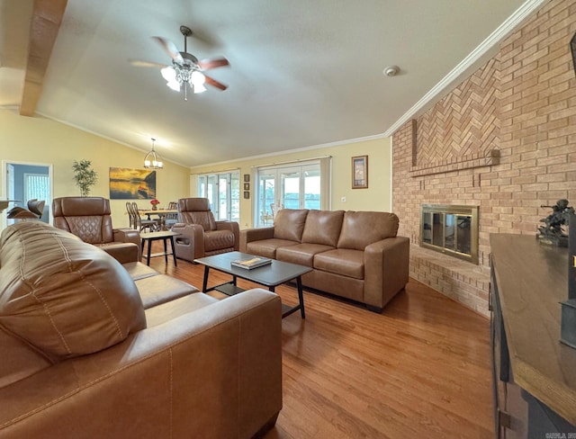 living area with a ceiling fan, light wood finished floors, a fireplace, lofted ceiling, and ornamental molding