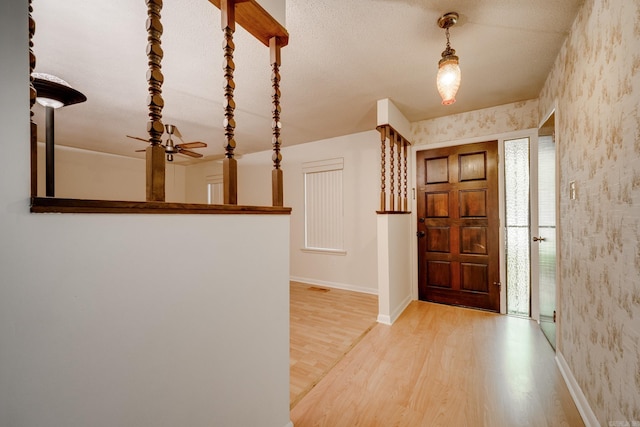 foyer featuring baseboards, wood finished floors, and wallpapered walls