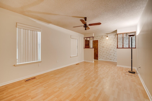 spare room featuring visible vents, wood finished floors, baseboards, ceiling fan, and a textured ceiling