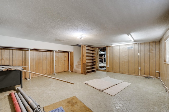 finished basement with tile patterned floors, a textured ceiling, and visible vents