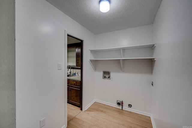 clothes washing area with laundry area, a textured ceiling, hookup for a gas dryer, light wood-type flooring, and hookup for a washing machine