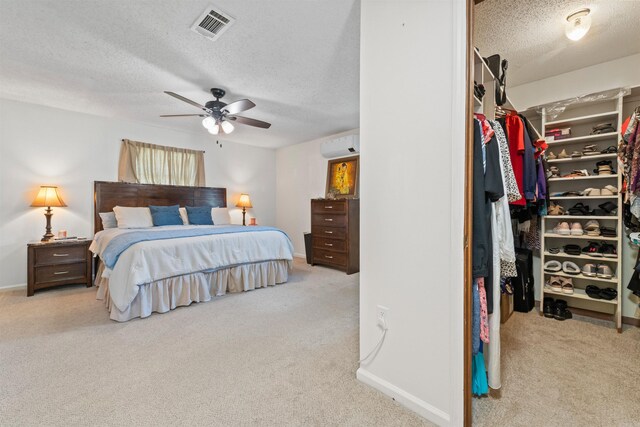 111 Pamela Ln, Sherwood, AR 72120 - carpeted bedroom featuring a wall mounted air conditioner, a spacious closet, visible vents, a textured ceiling, and ceiling fan
