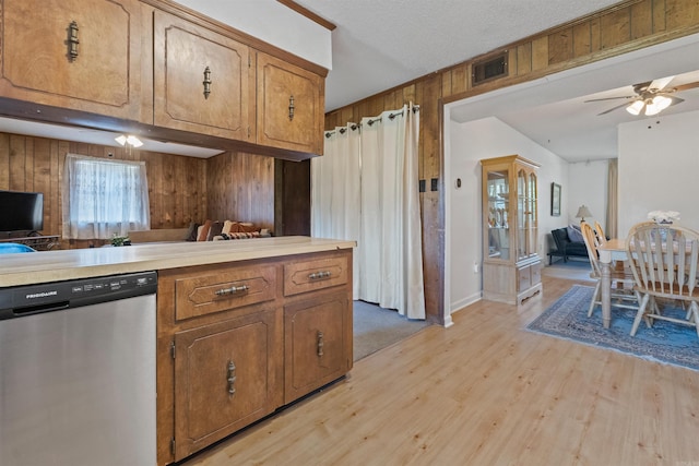 111 Pamela Ln, Sherwood, AR 72120 - kitchen featuring light wood finished floors, wood walls, visible vents, stainless steel dishwasher, and brown cabinetry