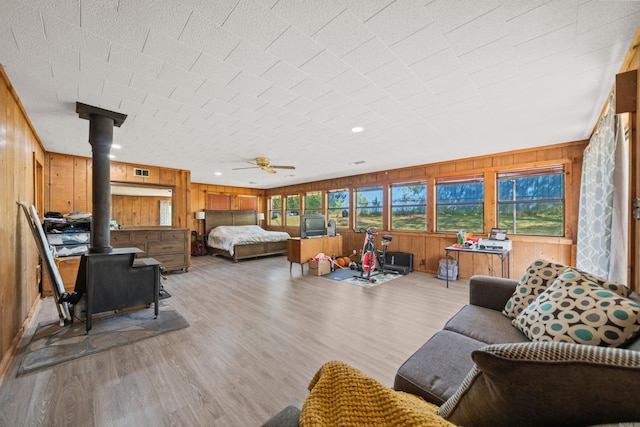 bedroom with wooden walls, wood finished floors, a wood stove, and visible vents