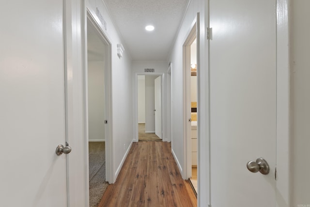 hall with visible vents, wood finished floors, baseboards, and recessed lighting