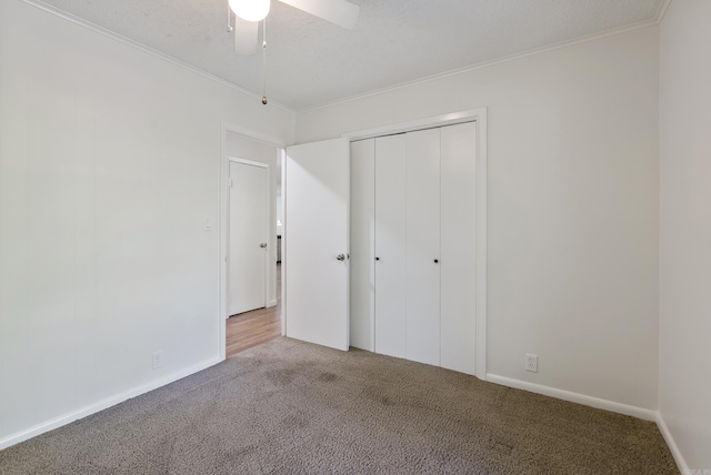 unfurnished bedroom featuring a ceiling fan, ornamental molding, carpet flooring, and a closet