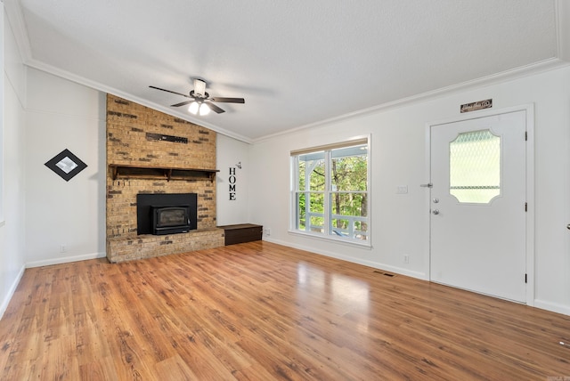 unfurnished living room featuring vaulted ceiling, visible vents, wood finished floors, ceiling fan, and a wood stove