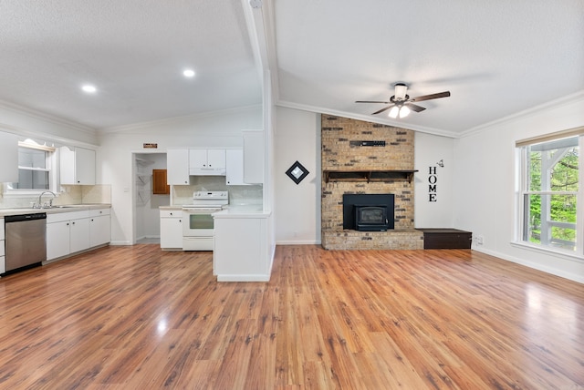 unfurnished living room featuring light wood finished floors, vaulted ceiling, a ceiling fan, a sink, and baseboards
