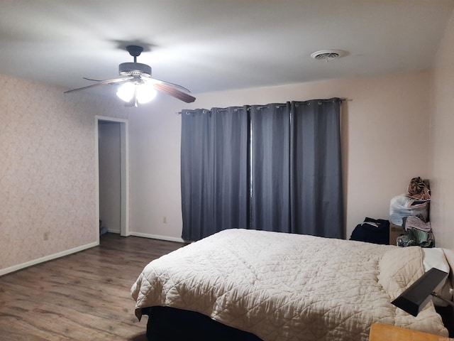bedroom with wallpapered walls, wood finished floors, visible vents, a ceiling fan, and baseboards