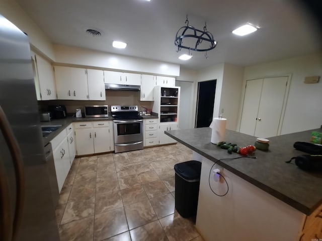 kitchen featuring dark countertops, visible vents, white cabinetry, under cabinet range hood, and appliances with stainless steel finishes