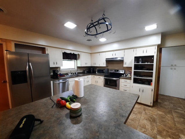 kitchen with dark countertops, under cabinet range hood, stainless steel appliances, and a sink