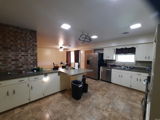 kitchen featuring dark countertops, a sink, stainless steel appliances, a peninsula, and visible vents