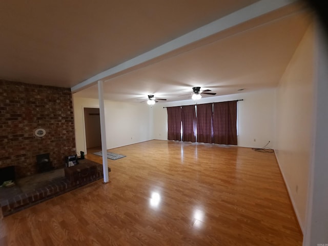 unfurnished living room featuring ceiling fan, baseboards, a brick fireplace, and light wood finished floors