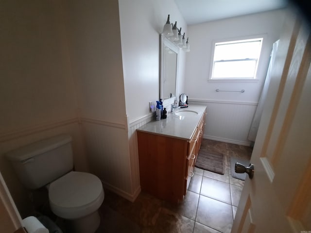 bathroom with wainscoting, tile patterned floors, vanity, and toilet