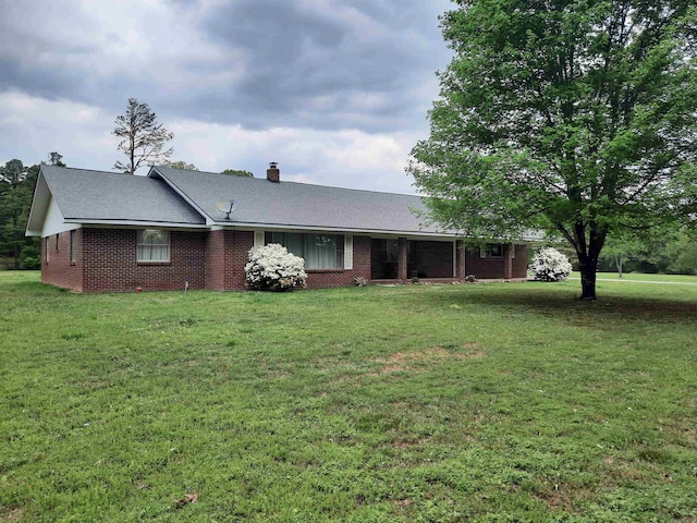 view of front of property with a chimney, brick siding, and a front yard