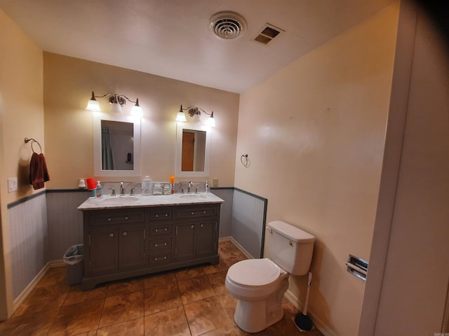 full bath featuring a wainscoted wall, visible vents, a sink, and toilet