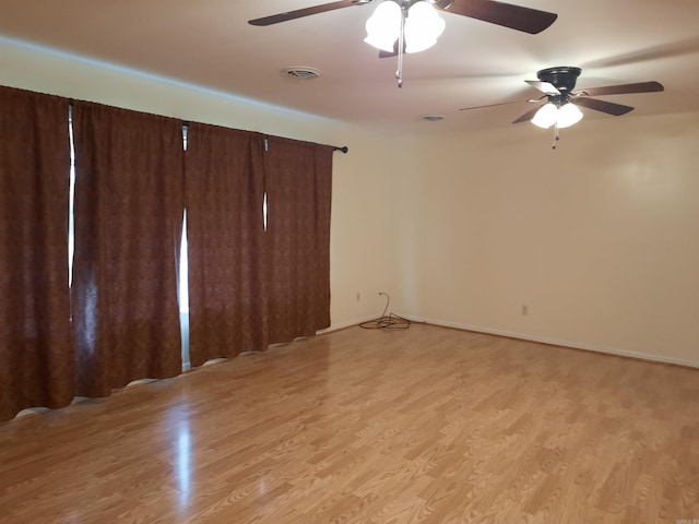 empty room with light wood-type flooring, a ceiling fan, and visible vents