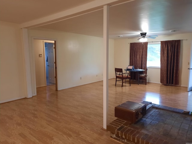 living area featuring wood finished floors, baseboards, and ceiling fan