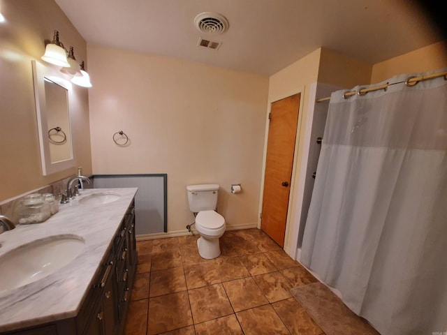 bathroom featuring toilet, a sink, visible vents, and double vanity