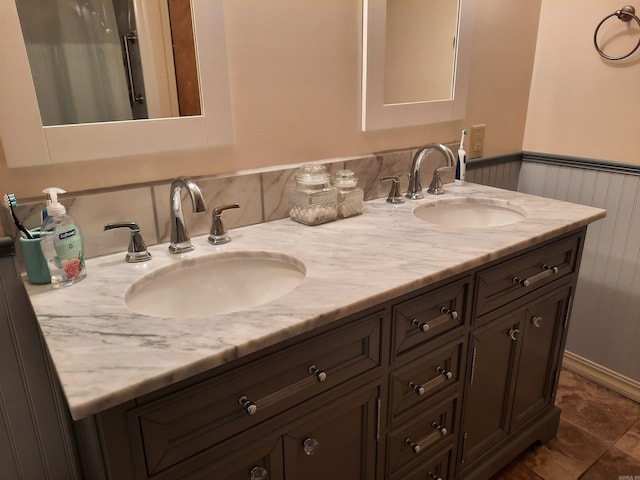full bathroom with wainscoting, a sink, and double vanity