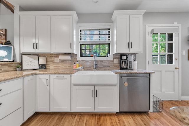 kitchen with white cabinets, stainless steel dishwasher, decorative backsplash, and a sink