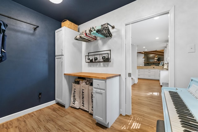 kitchen with wood counters, baseboards, white cabinetry, and light wood-style floors