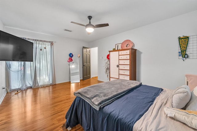 bedroom featuring baseboards, light wood-style flooring, visible vents, and ceiling fan