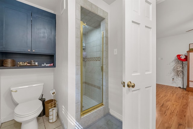 bathroom featuring toilet, wood finished floors, baseboards, and a stall shower