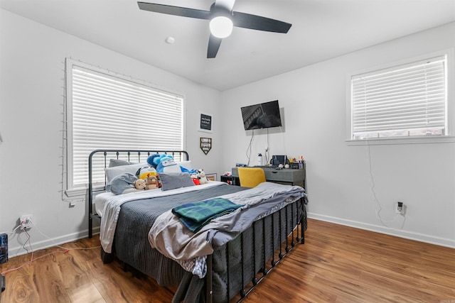 bedroom featuring baseboards, wood finished floors, and multiple windows