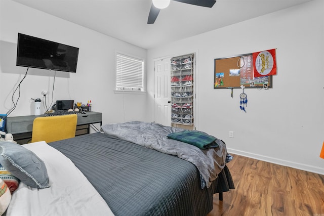bedroom with baseboards, a ceiling fan, wood finished floors, and a closet
