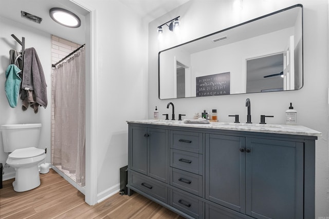 full bathroom featuring toilet, wood finished floors, a sink, and visible vents
