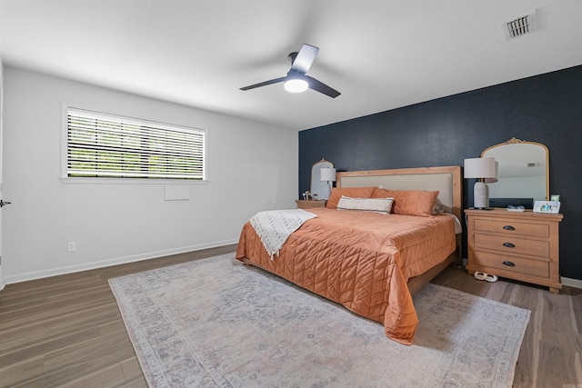 bedroom featuring visible vents, baseboards, a ceiling fan, and wood finished floors
