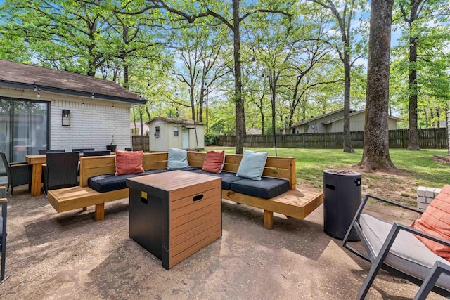 view of patio featuring a fenced backyard, an outdoor structure, outdoor dining area, and a shed