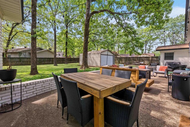view of patio with a fenced backyard, a storage unit, and outdoor dining area