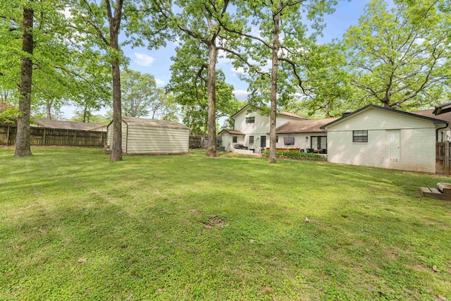 view of yard with a storage unit, an outbuilding, and a fenced backyard