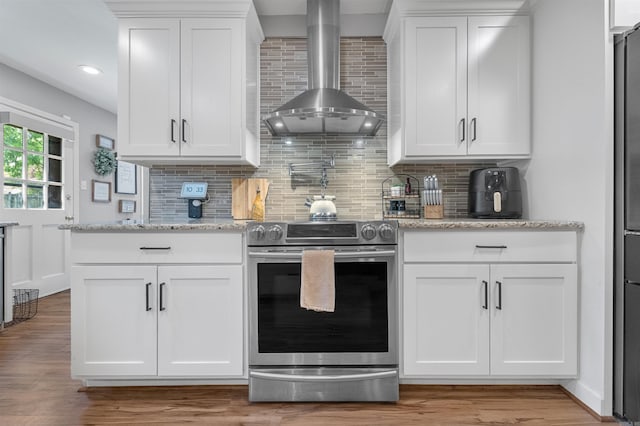 kitchen with wall chimney exhaust hood, white cabinets, appliances with stainless steel finishes, and tasteful backsplash