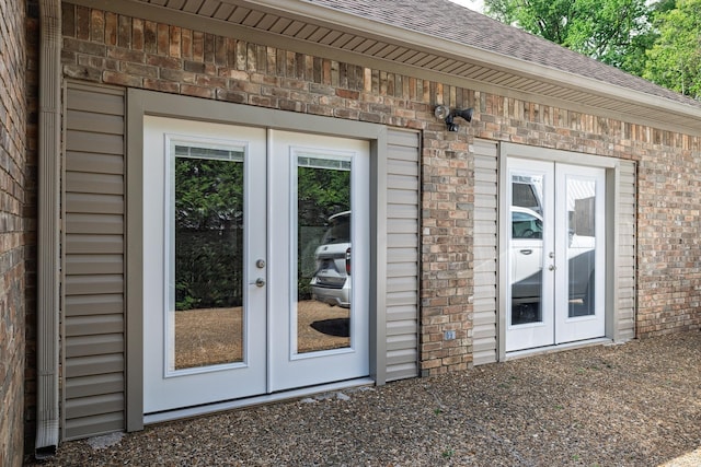 property entrance with a shingled roof, french doors, and brick siding