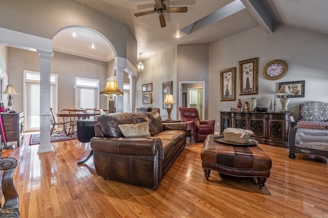 living room with high vaulted ceiling, light wood-style floors, ceiling fan, arched walkways, and decorative columns