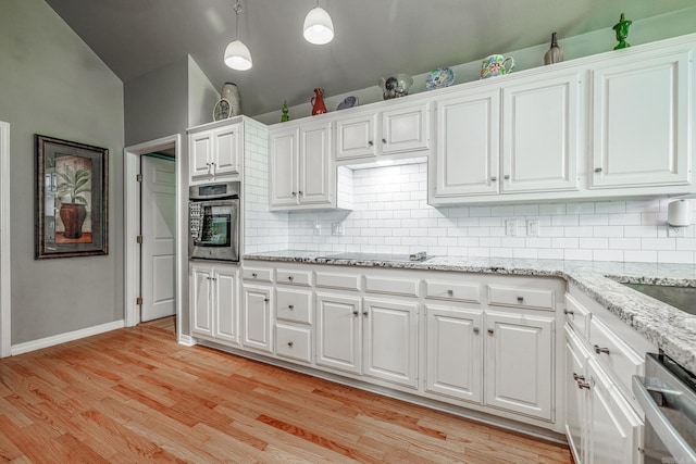 kitchen with white cabinets, light wood-style floors, decorative backsplash, and stainless steel appliances